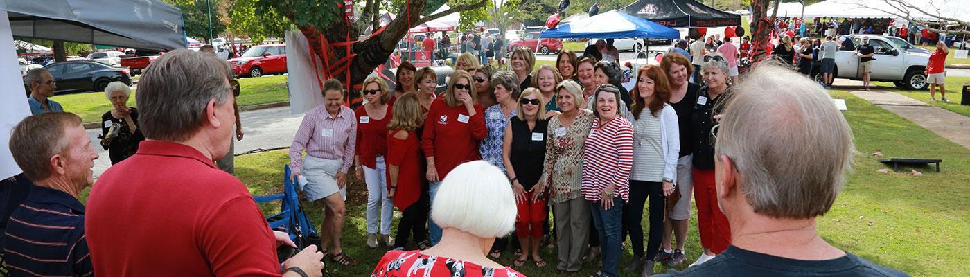 Two dozen female alumni posing as a group under a tree on campus